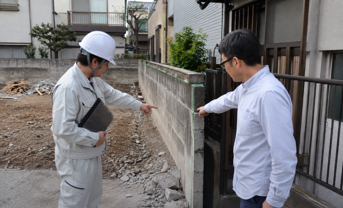 解体後も残す境界塀を施主と担当者が確認する様子