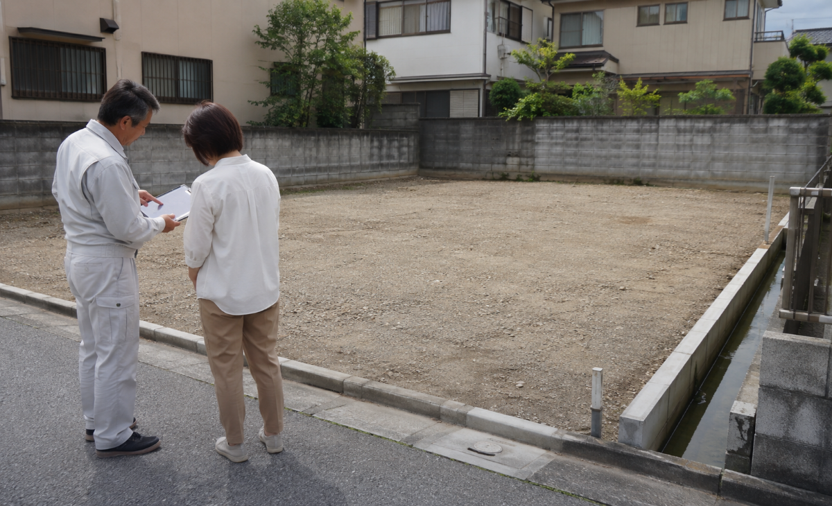 解体後の整地と側溝を施主と担当者が完了確認する様子