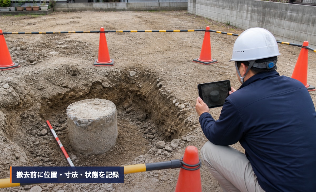 発見された地中杭を安全区画の外から記録する様子